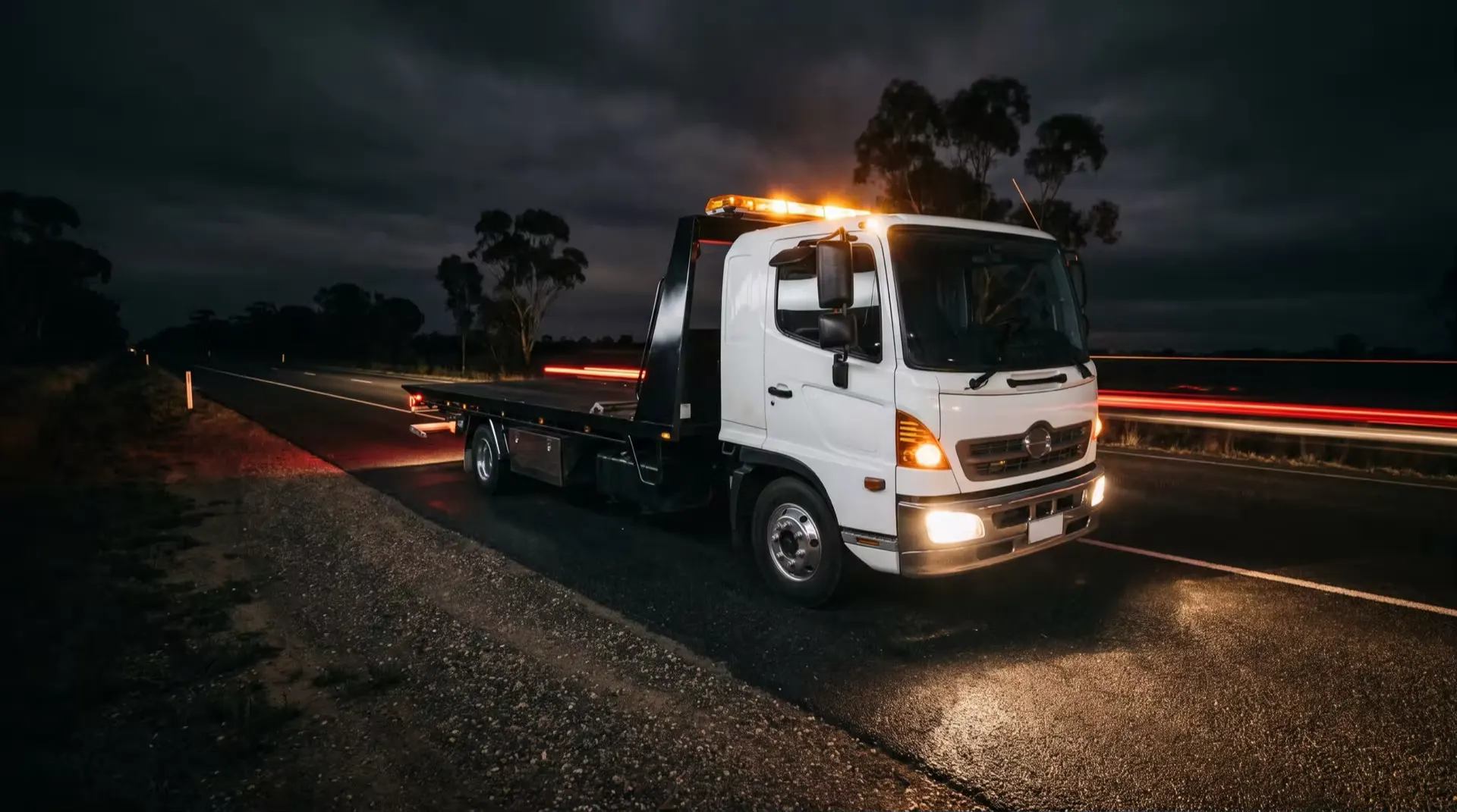 Evolution Towing tilt tray truck parked on a dark Hunter Valley highway at night, beacon glowing