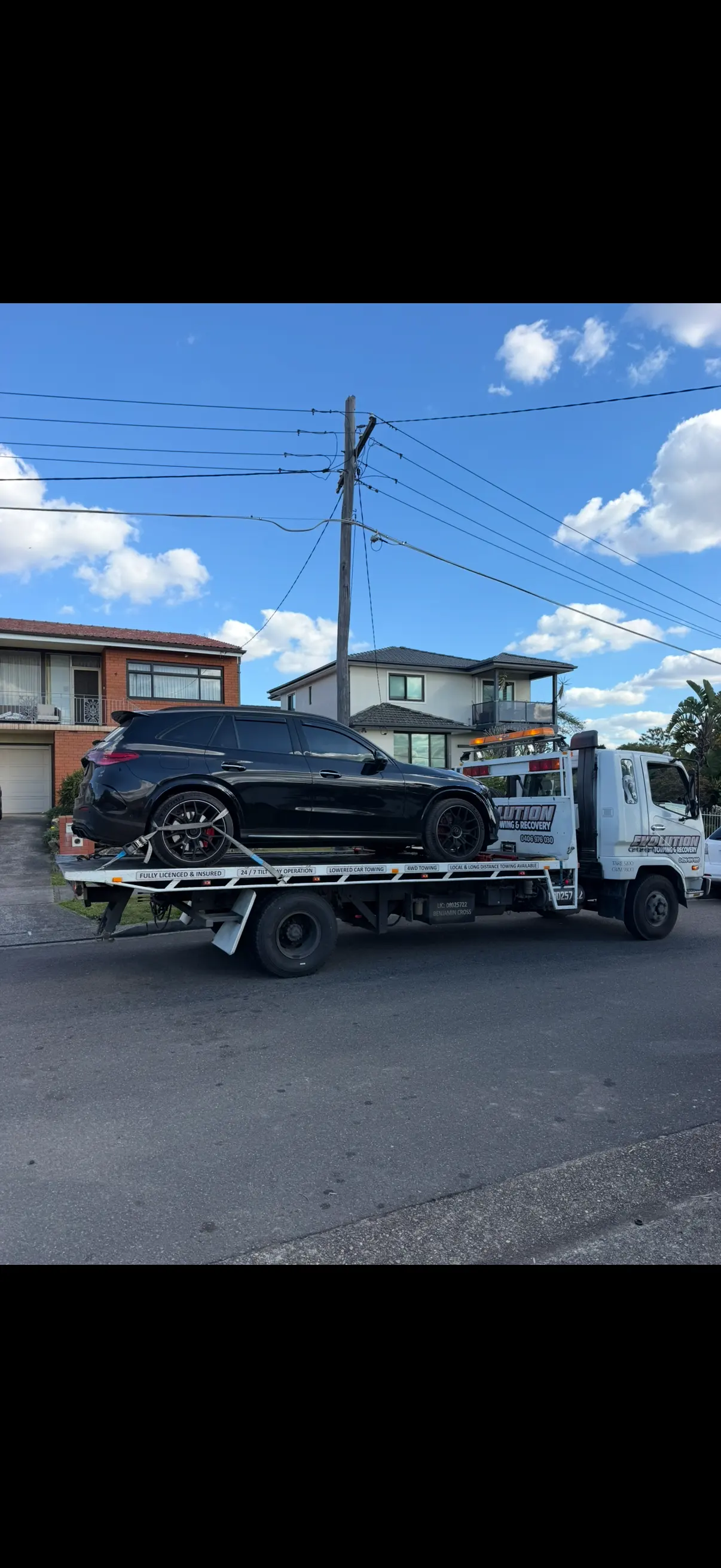 Black Mercedes SUV secured on the Evolution tilt tray in a suburban street