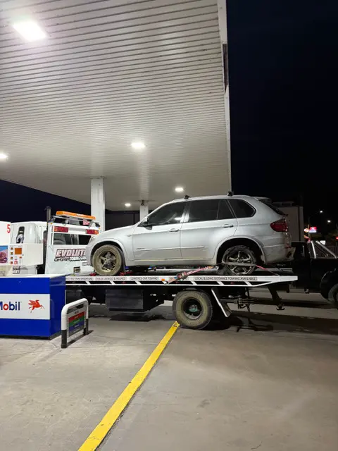 Silver BMW X5 on the Evolution tilt tray under service station lights at night