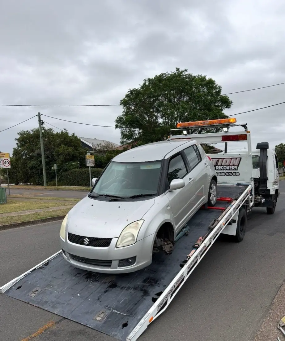 Suzuki Swift being winched onto the tilted tray in a suburban street