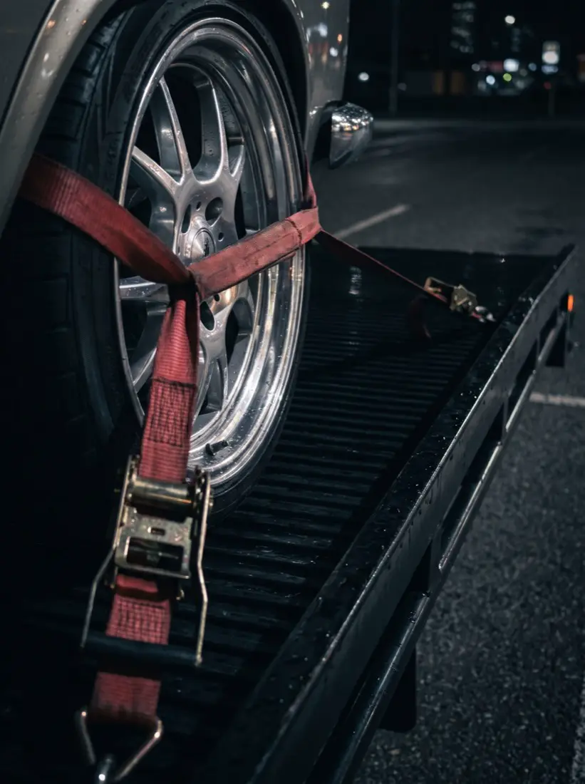 Red soft strap secured over the alloy wheel of a lowered classic car